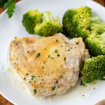 One piece of Amish Chicken on a white plate with broccoli.