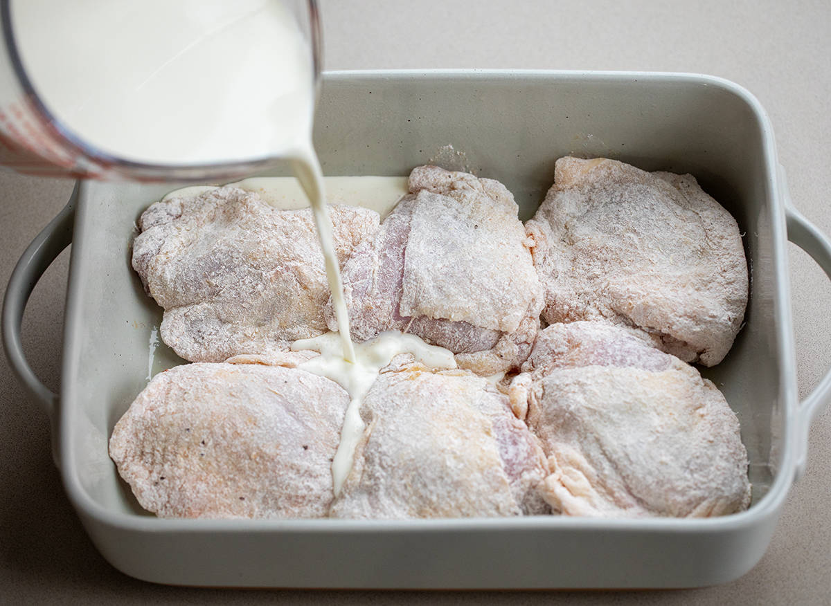 Pouring over skins on chicken thighs in a baking dish.