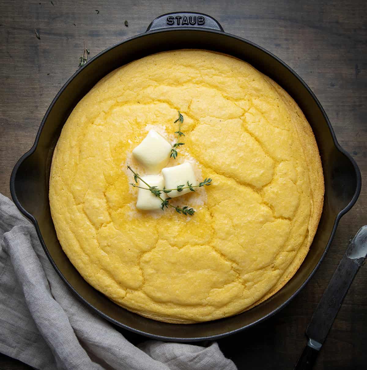 Country Homestyle Cornbread in a skillet on a wooden table from overhead.