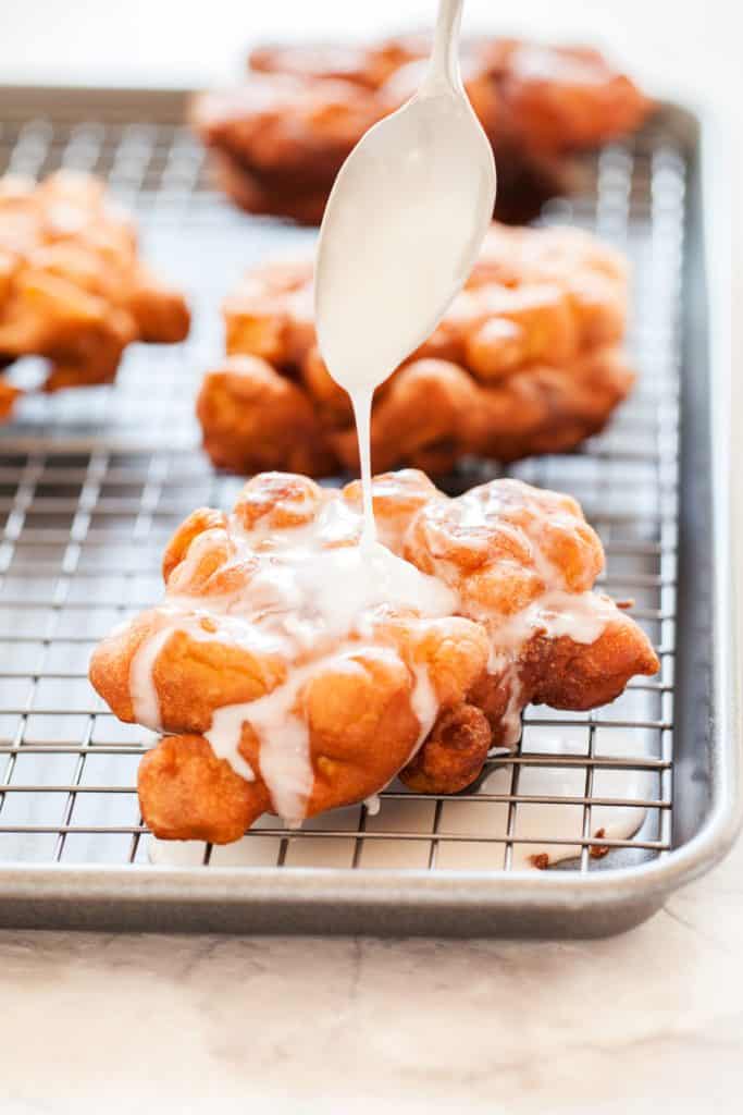 Drizzling Glaze over Apple Fritters on a wire rack