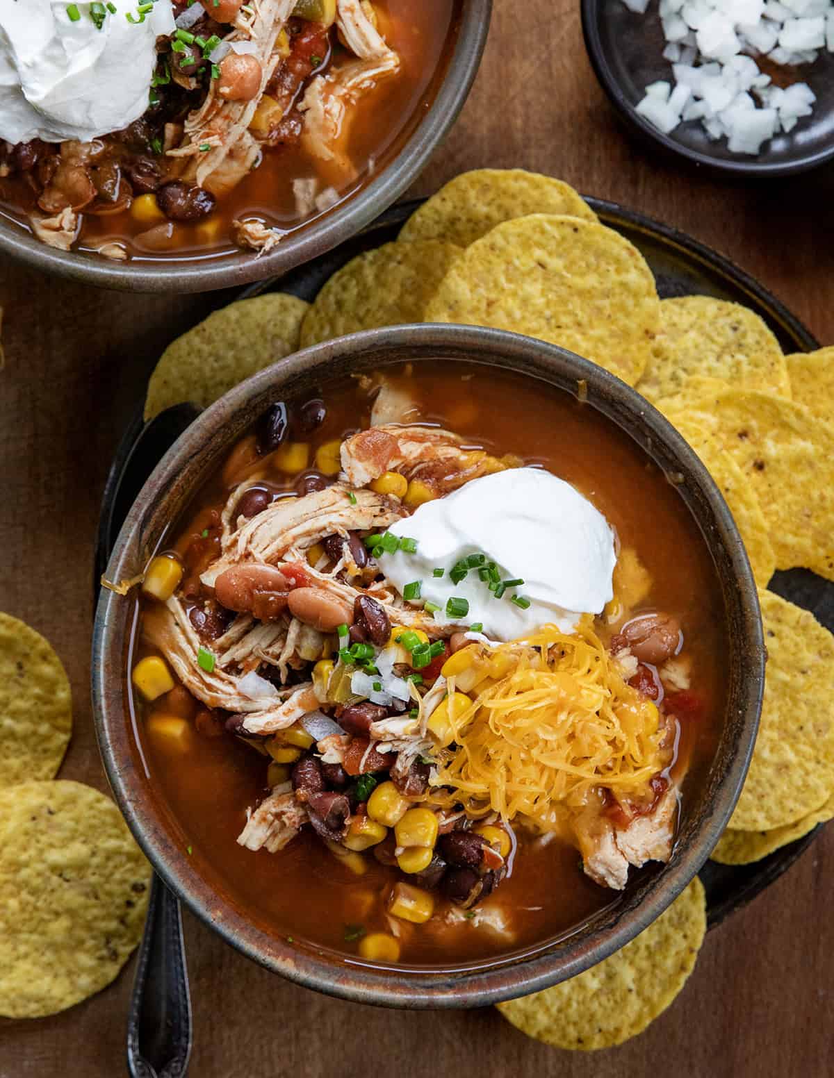Bowls of Slow Cooker Chicken Taco Soup on a wooden table from overhead.