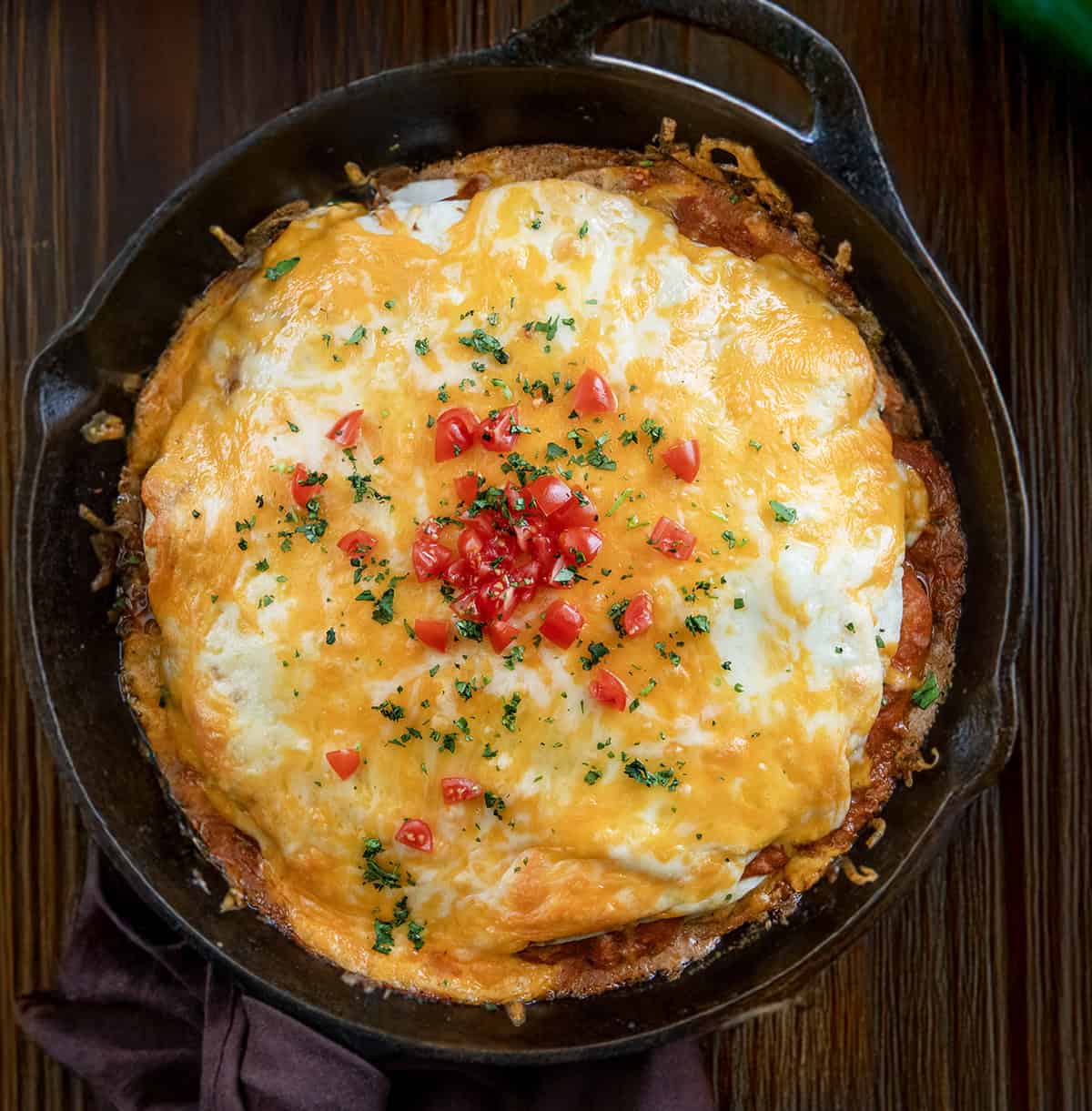 Skillet of Chicken Tortilla Casserole on a wooden table from overhead.
