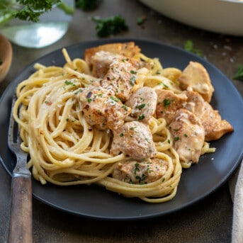 Plate of Creamy Chicken Pasta with a Wooden Fork on a Dark Table.