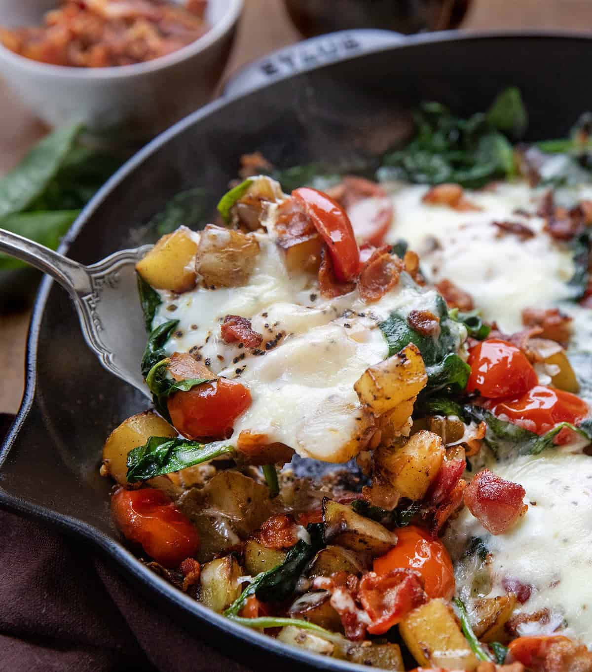 Spoon picking up a portion of Breakfast Skillet Spinach and Eggs from the skillet Spoon picking up a portion of Breakfast Skillet Spinach and Eggs from the skillet.