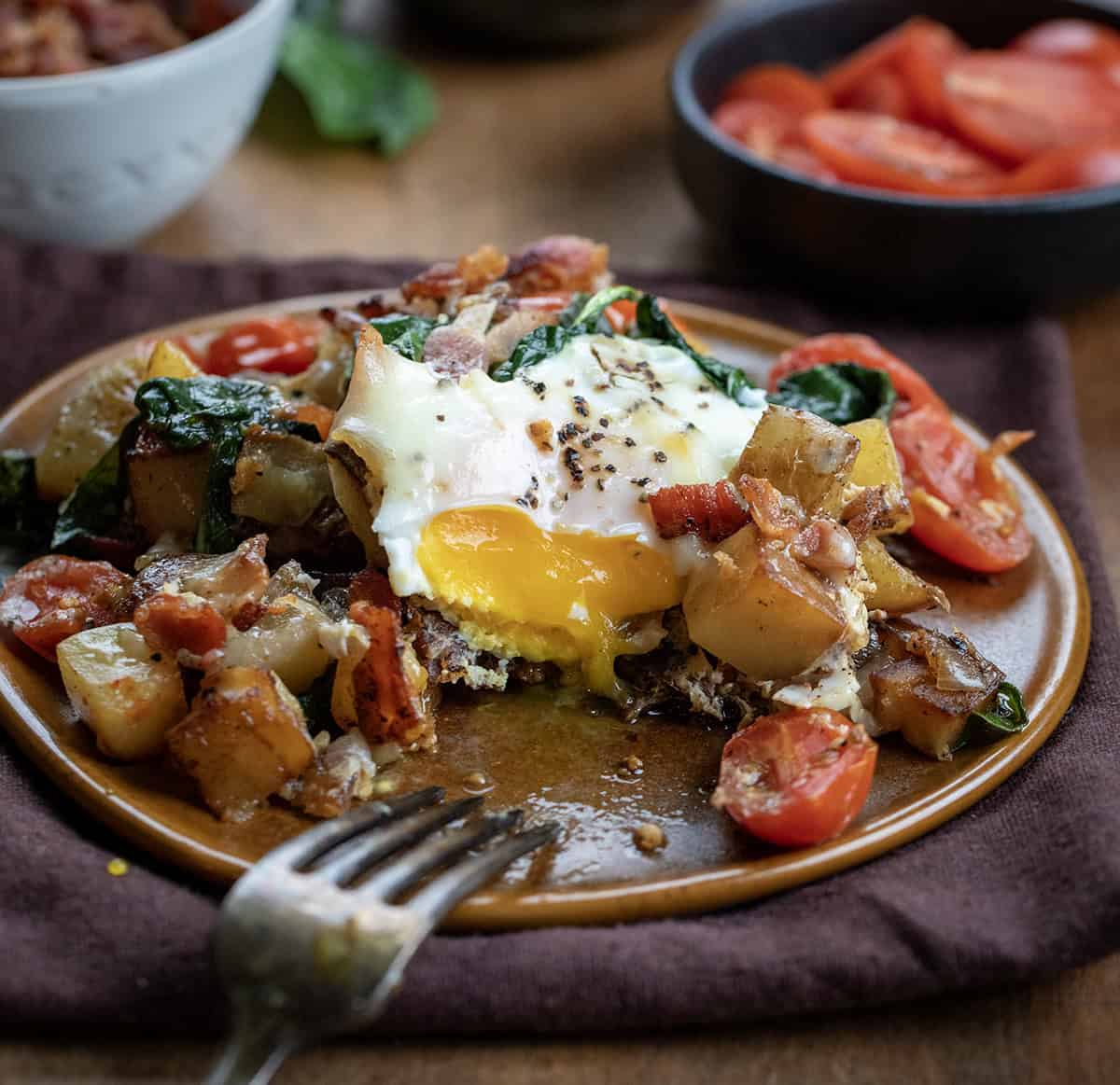 Portion of Breakfast Skillet Spinach and Eggs with a bite taken out of the egg showing the runny filling Portion of Breakfast Skillet Spinach and Eggs with a bite taken out of the egg showing the runny filling.