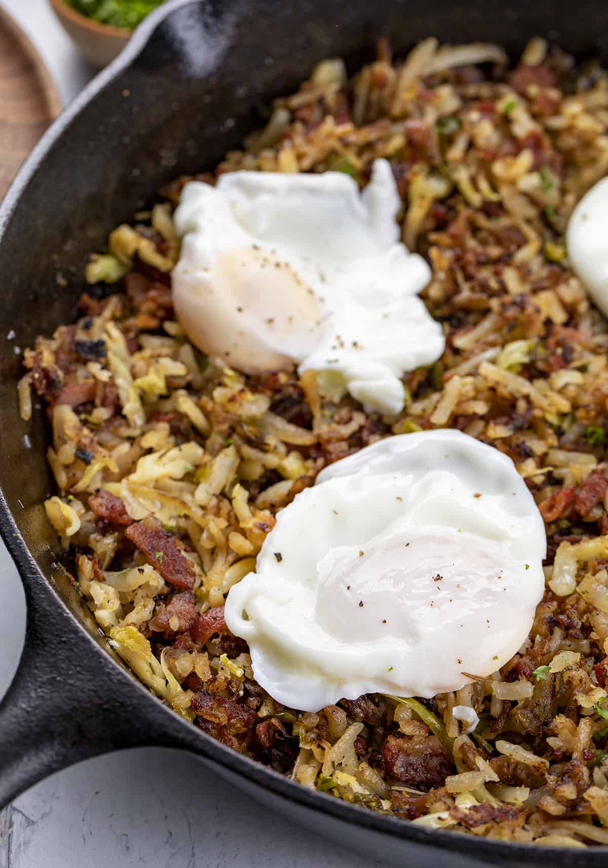 Side of a Skillet Full of Brussels Sprout Breakfast Hash with Poached Eggs. Breakfast, Hash, How to Make Hash, Poached Egg, How to Poach and Egg, breakfast recipes, i am homesteader, iamhomesteader.