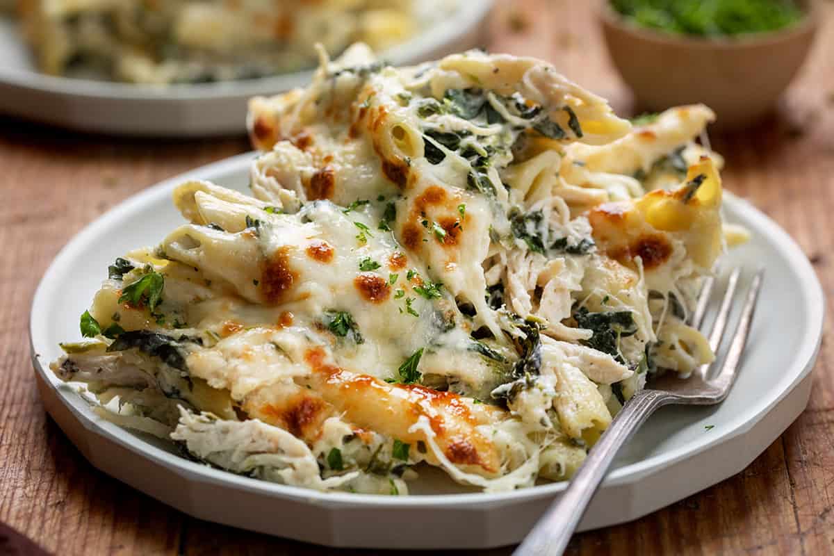 Spinach Dip Chicken Pasta on a plate on a wooden table.
