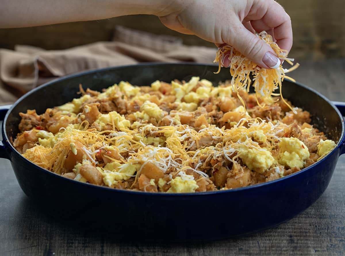 Adding finely shredded cheese over baked Pulled Pork Hash.