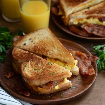 Griddle Breakfast Sandwich cut in half on a plate with another sandwich in the background.