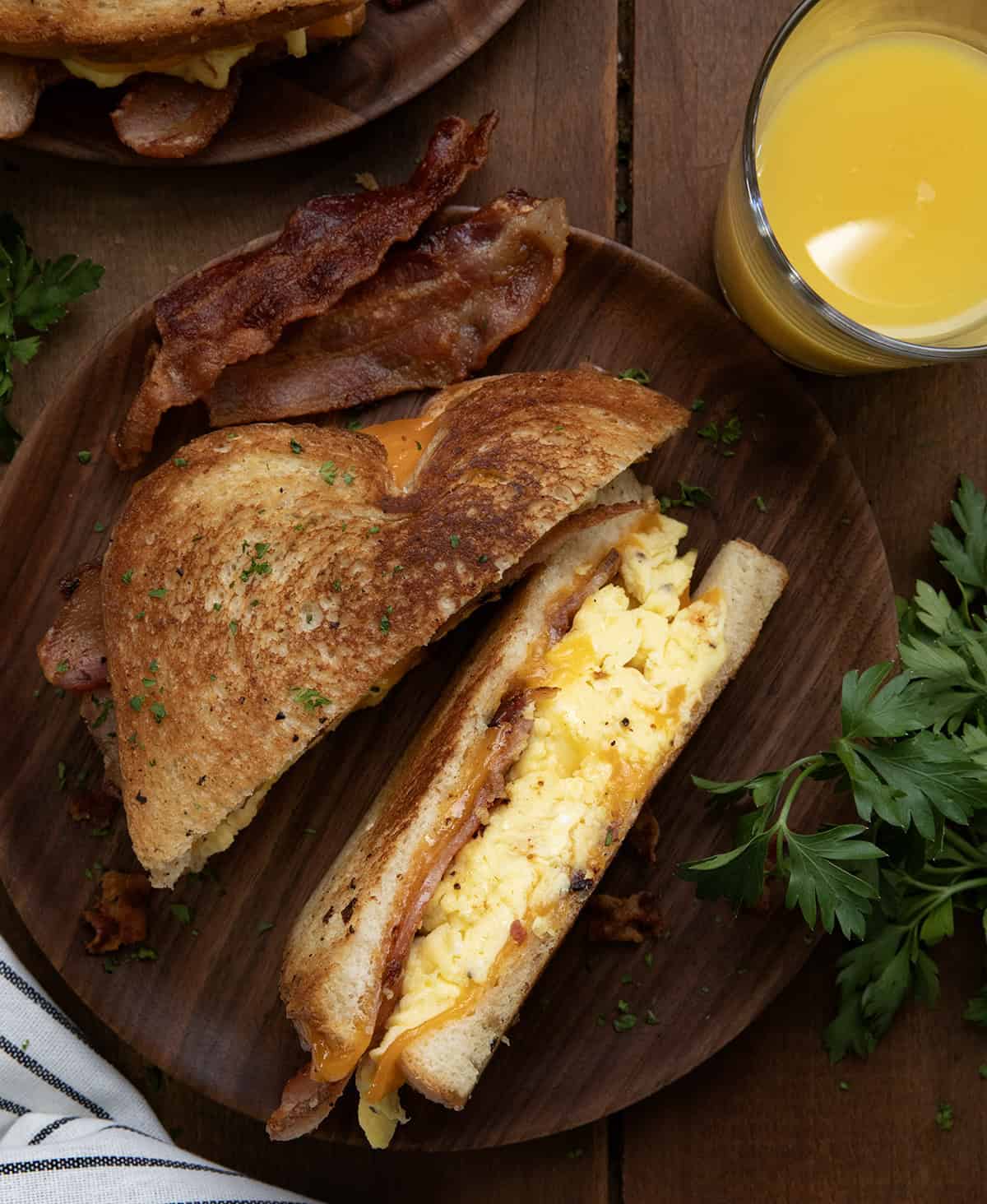 Cut in half Griddle Breakfast Sandwich on a wooden table from overhead with a glass of orange juice. 