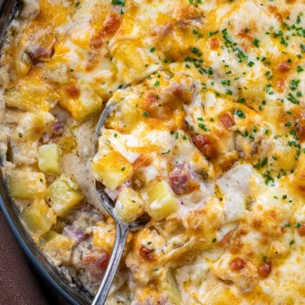 Spoon resting in a skillet of Ham and Potato Casserole.