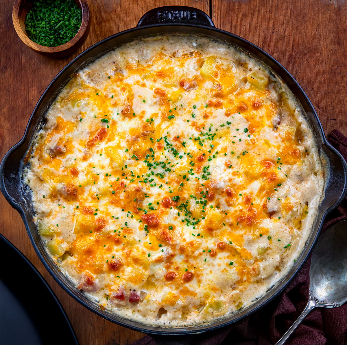 Skillet of Ham and Potato Casserole on a wooden table from overhead.