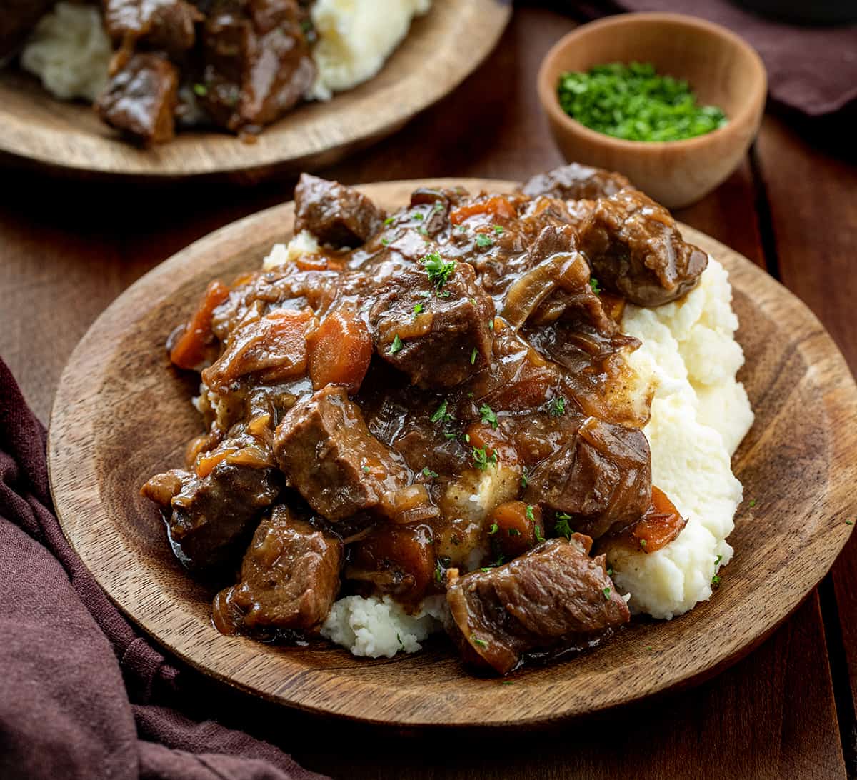 Plates of Slow Cooker Pot Roast over mashed potatoes.