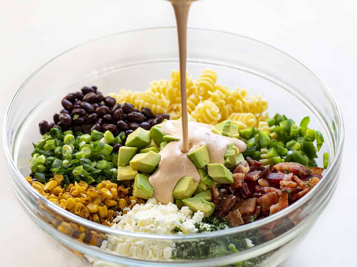Adding Dressing to Corn Pasta Salad in a Bowl
