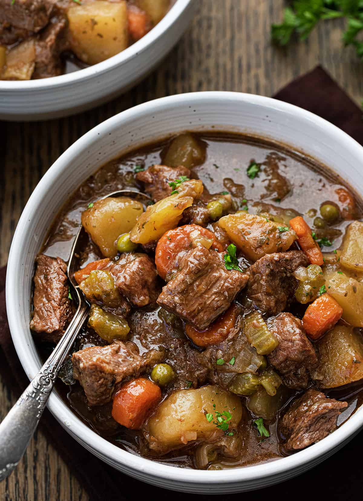 Close up of beef stew in a bowl showing the meat and potatoes and vegetables.