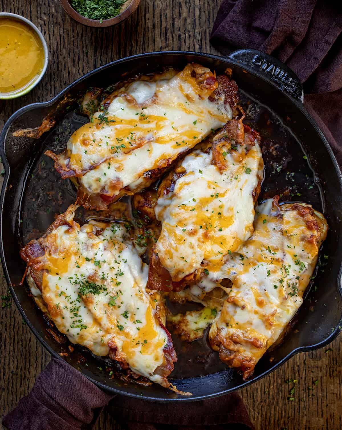 Cheesy Bacon Chicken with Mustard Sauce i a Black Skillet on a Wooden Cutting Bard.