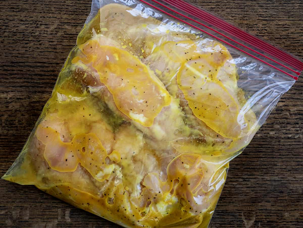 Bag of Raw Chicken on a Cutting Board with Cheesy Bacon Chicken with Mustard Sauce Marinade.