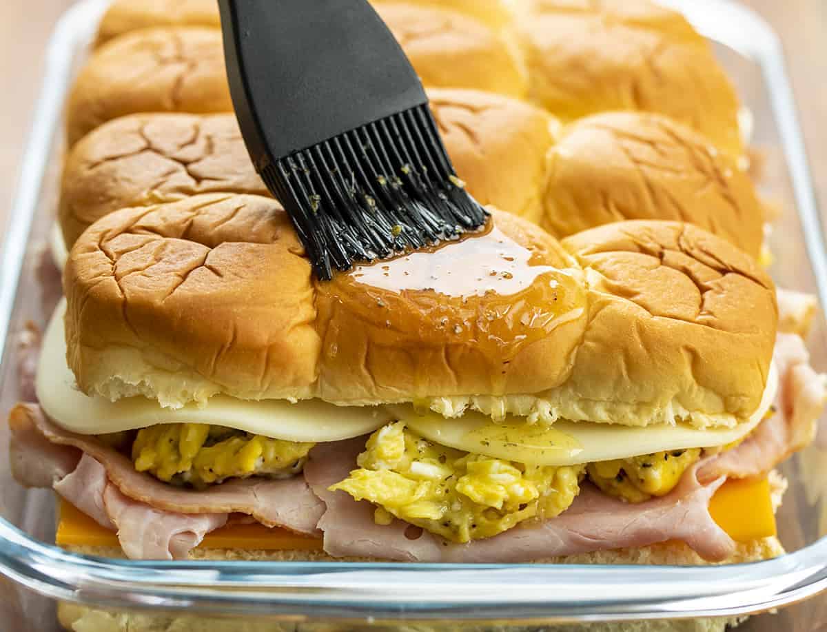 Brushing Top of Breakfast Sliders with Ham, Cheese, and Scrambled Egg with Seasoned Butter