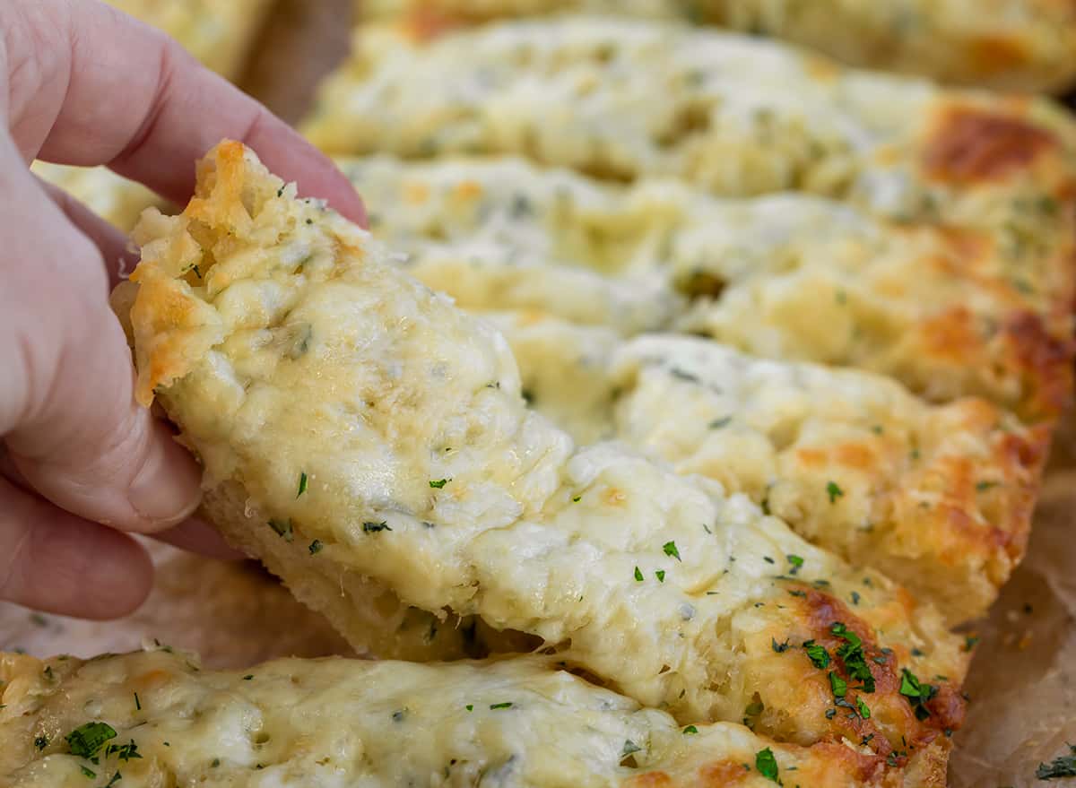 Hand picking up a slice of Garlic Cheese Bread.