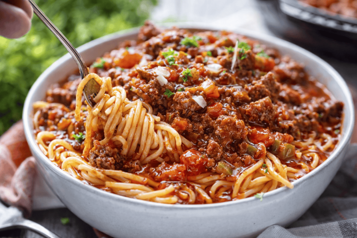 Homemade Spaghetti with Meat Sauce should be hearty and thick and filled with ground beef and veggies and the sweet and savory taste of tomatoes! Fork twirling spaghetti from a bowl of Homemade Spaghetti with Meat Sauce.