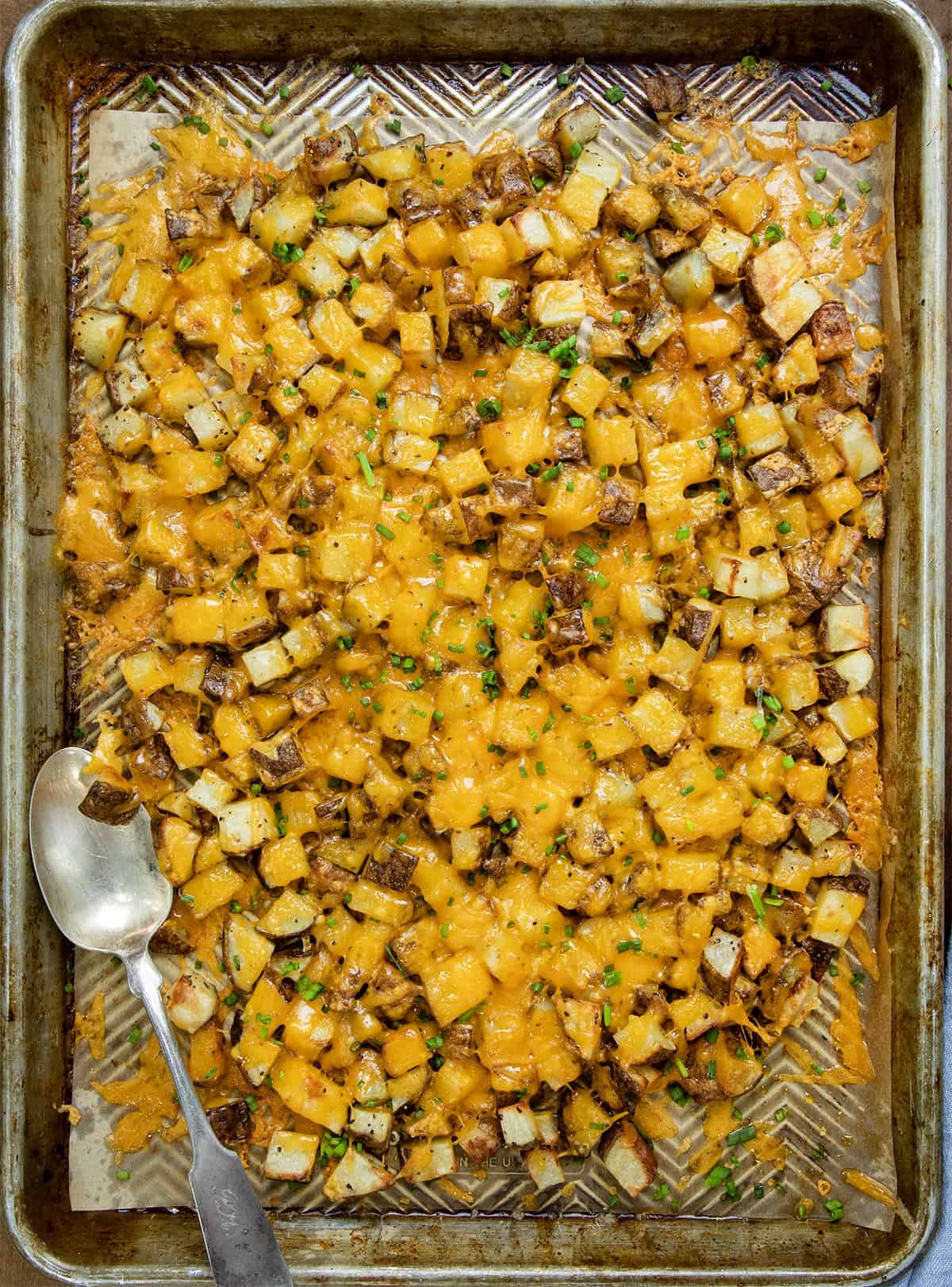 Pan of Cheesy Roasted Potatoes with a serving spoon from overhead.