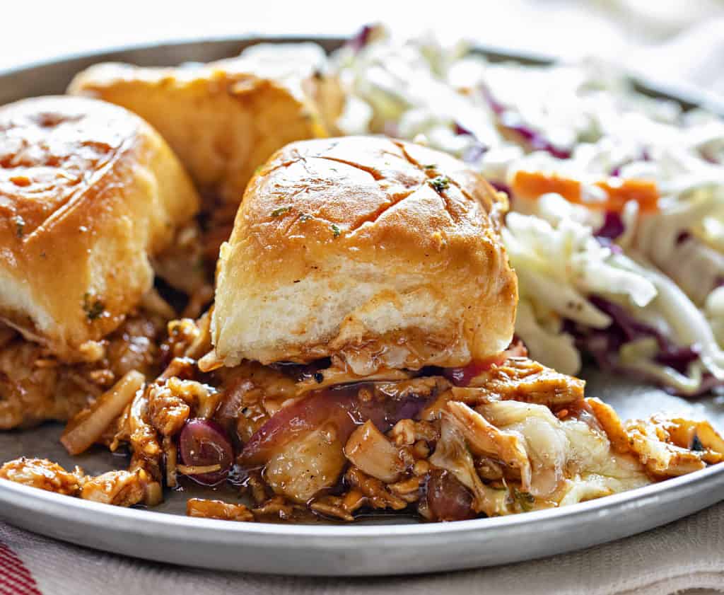 Sliders are one of the easiest ways to feed a crowd. They’re fun, customizable, and perfect for parties, game days, holidays, and family dinners! BBQ Chicken Sliders on a plate with coleslaw.