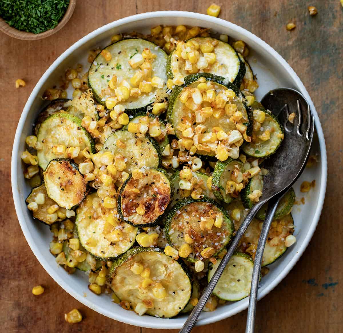 Bowl of Roasted Zucchini and Corn with spoons from overhead.