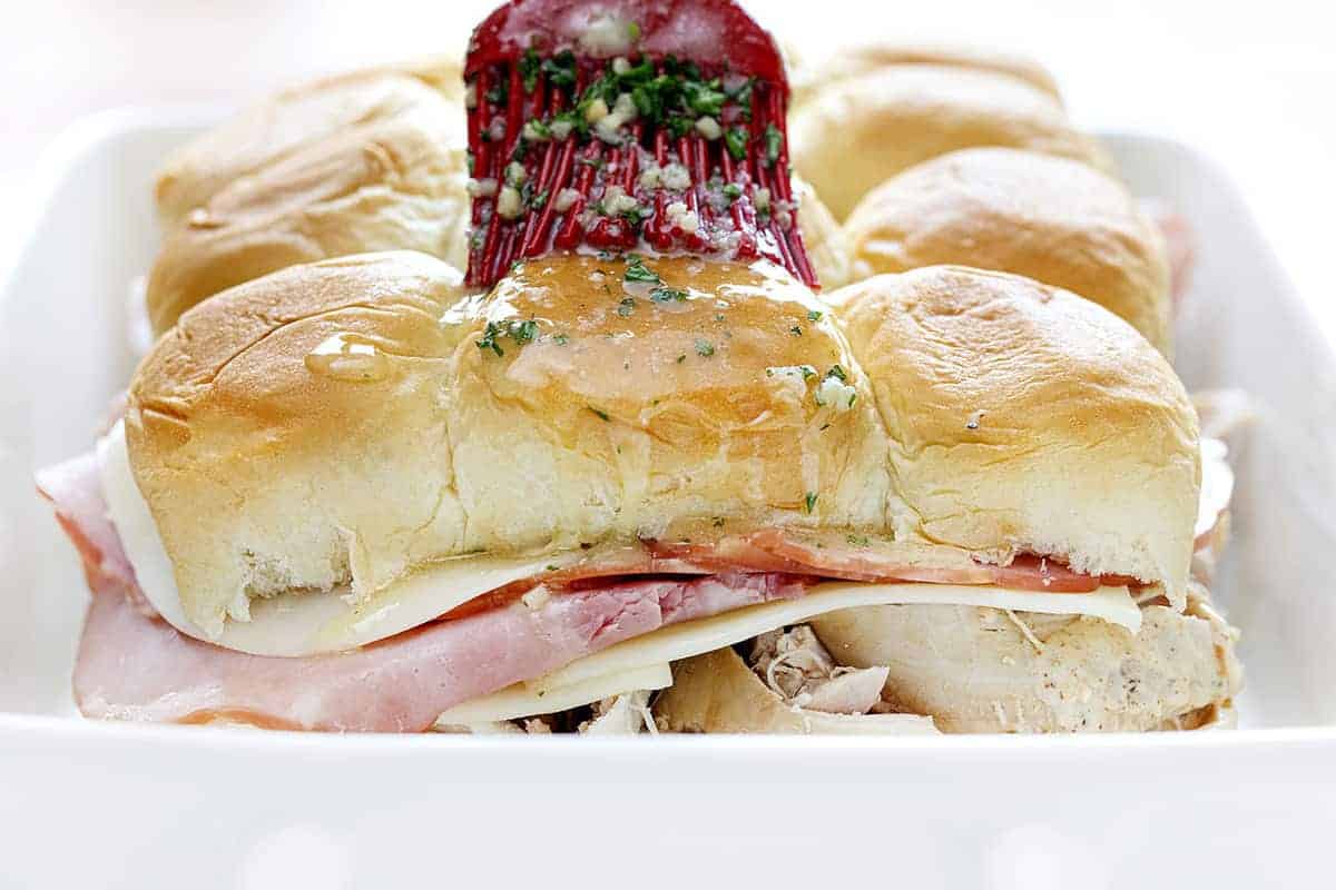 Spreading melted butter mix on chicken cordon bleu sliders