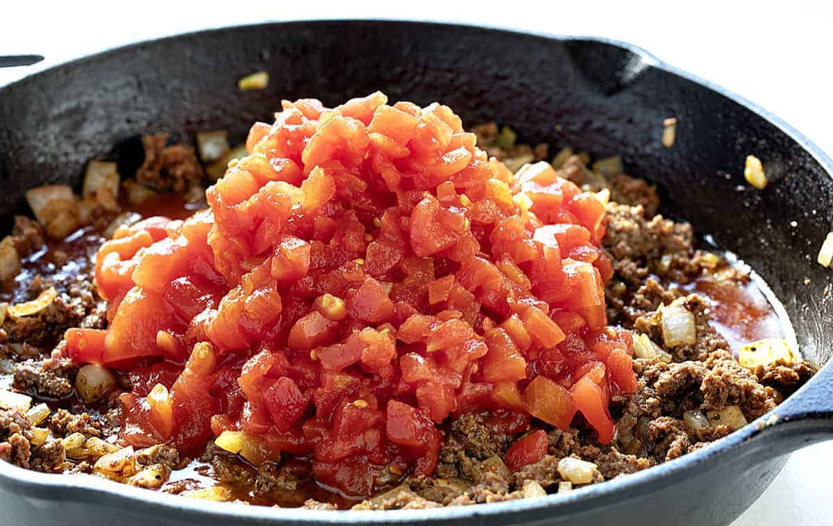 Making Taco Chili, adding tomatoes to meat