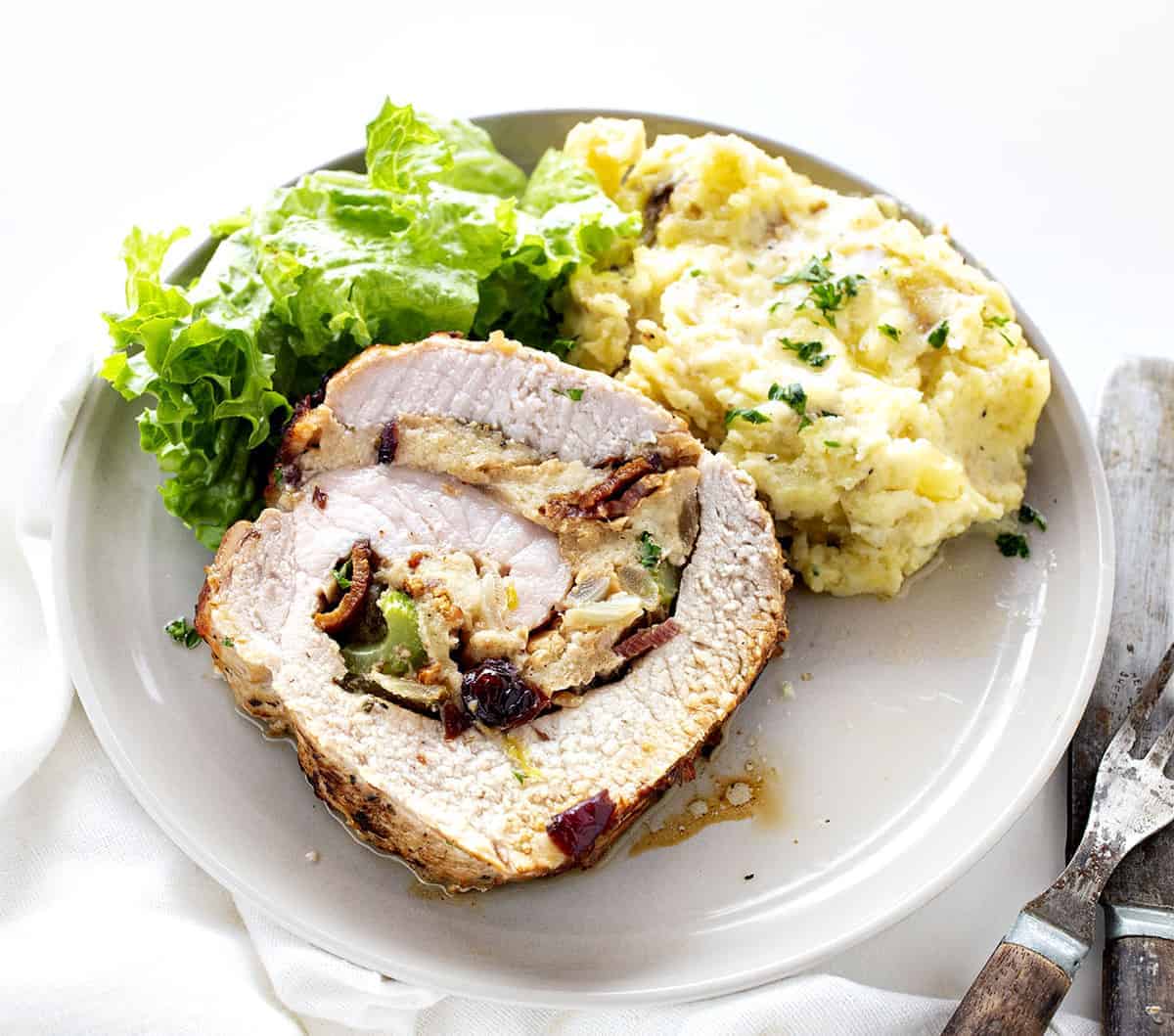 Cut Piece of Stuffed Pork Loin on a White Plate with Potatoes