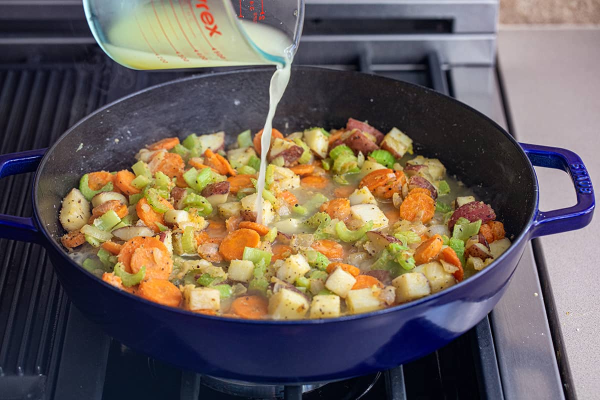 Pouring Stock into Vegetables in a Skillet for Chicken Pot Pie Casserole.