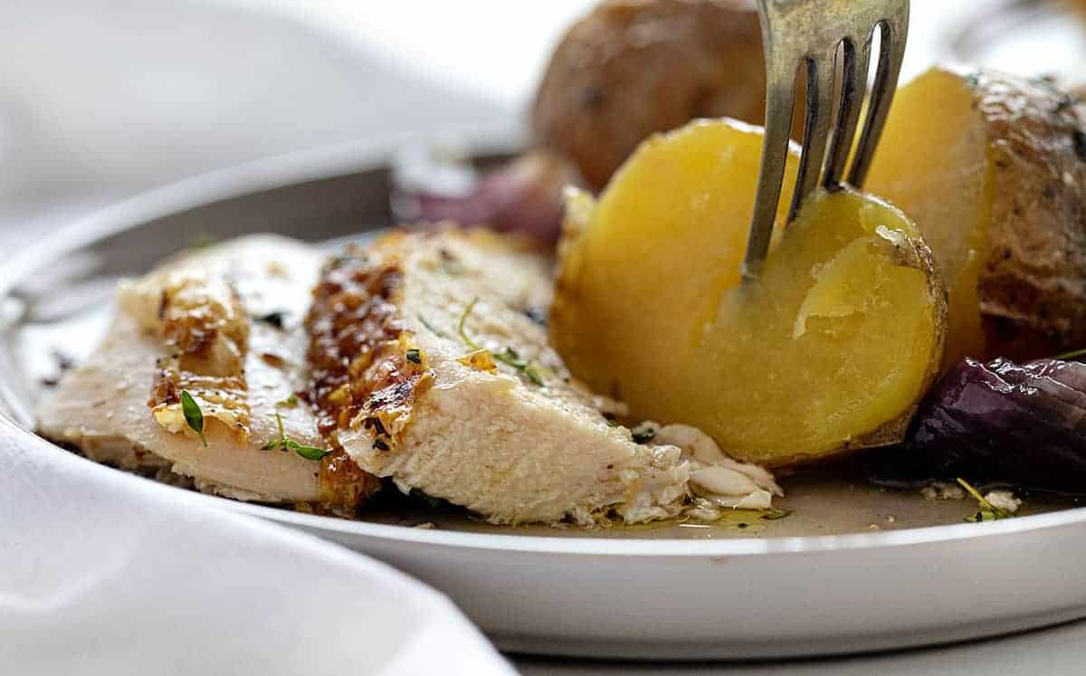 Fork stabbing potato and plated Roasted Chicken