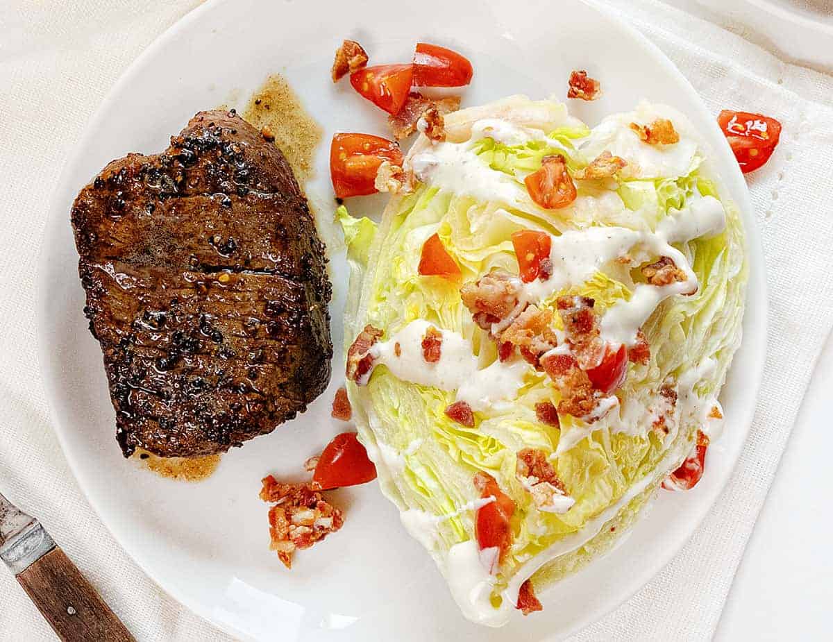 Overhead view of Pepper Crusted Tenderloin on a White Plate with a Wedge Salad