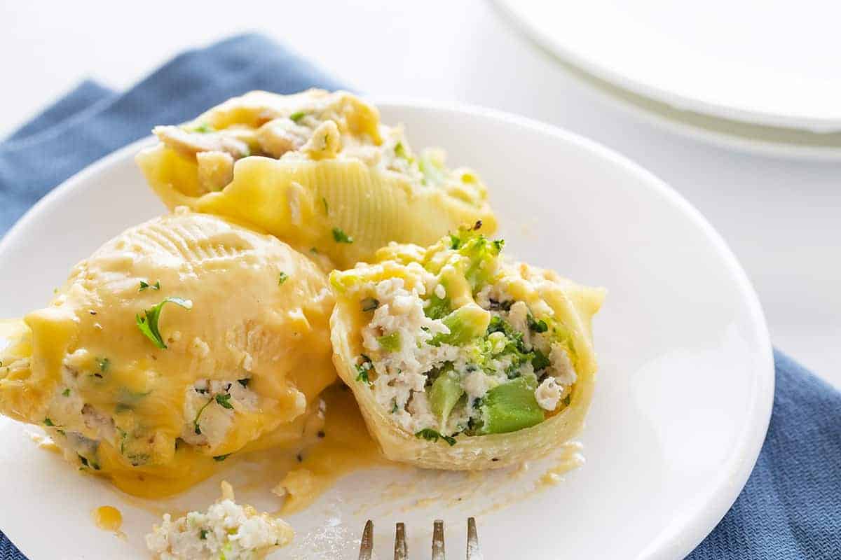 Cut Into Chicken Broccoli Stuffed Shells on White Plate with Blue Napkin