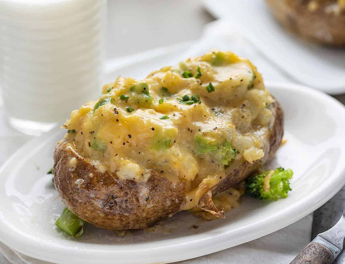 Broccoliost två gånger bakad potatis på en tallrik med mjölkglas bakom