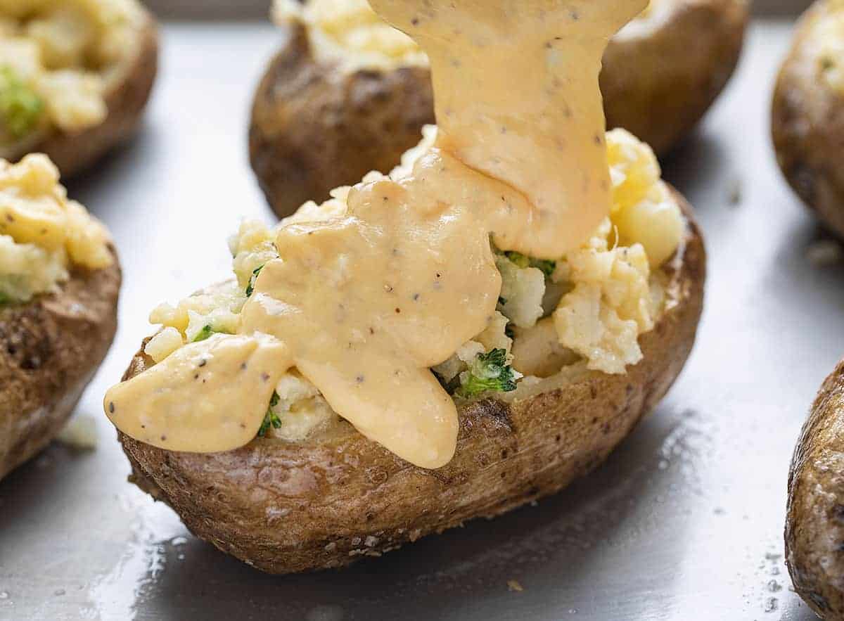 Broccoli Cheese Twice Baked Potato with Cheese Sauce Being Poured OVer Top