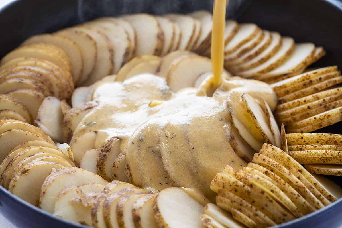 Pouring Cheese Sauce over Scalloped Potatoes