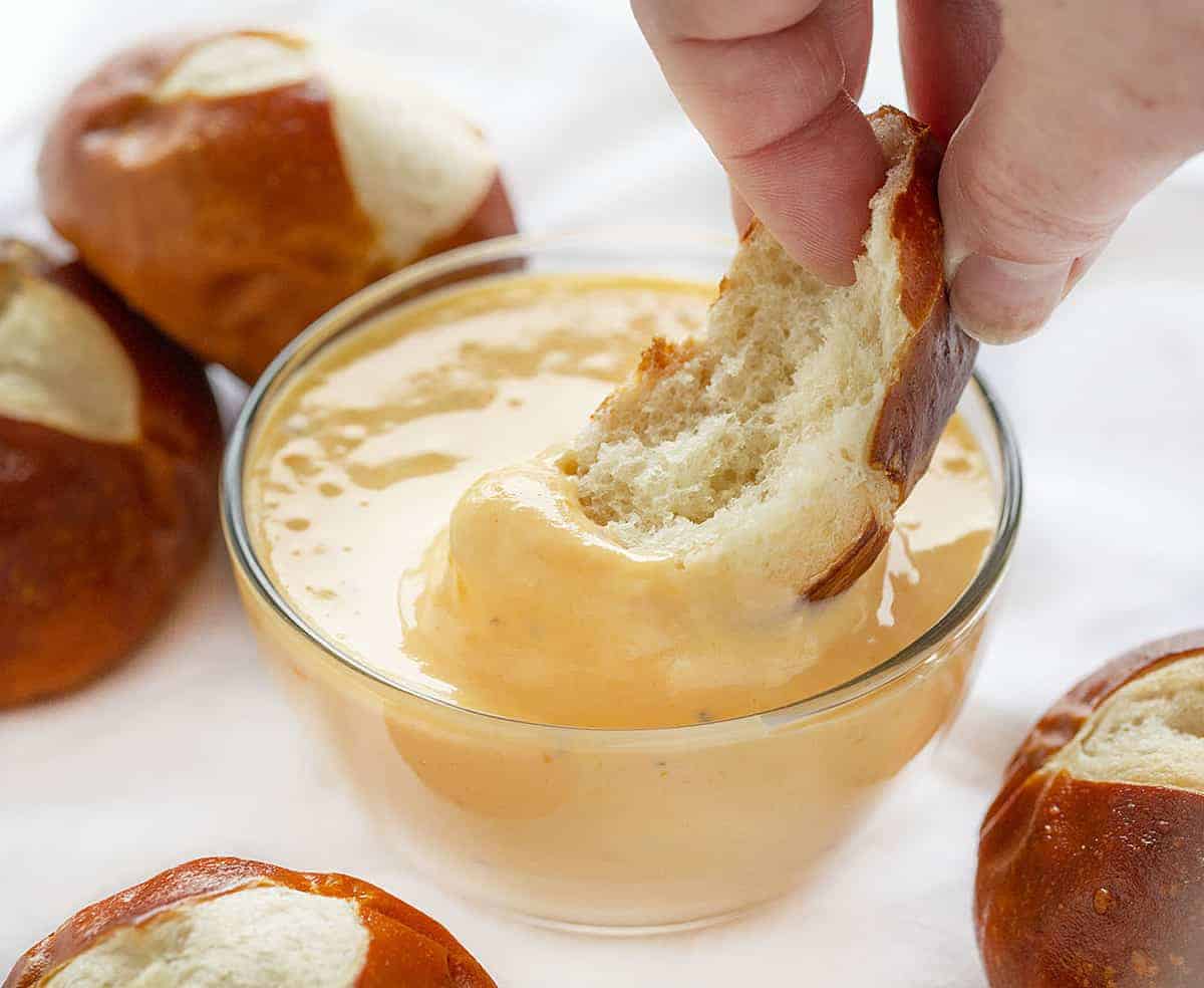 Dipping Pretzel into Cheddar Cheese Sauce