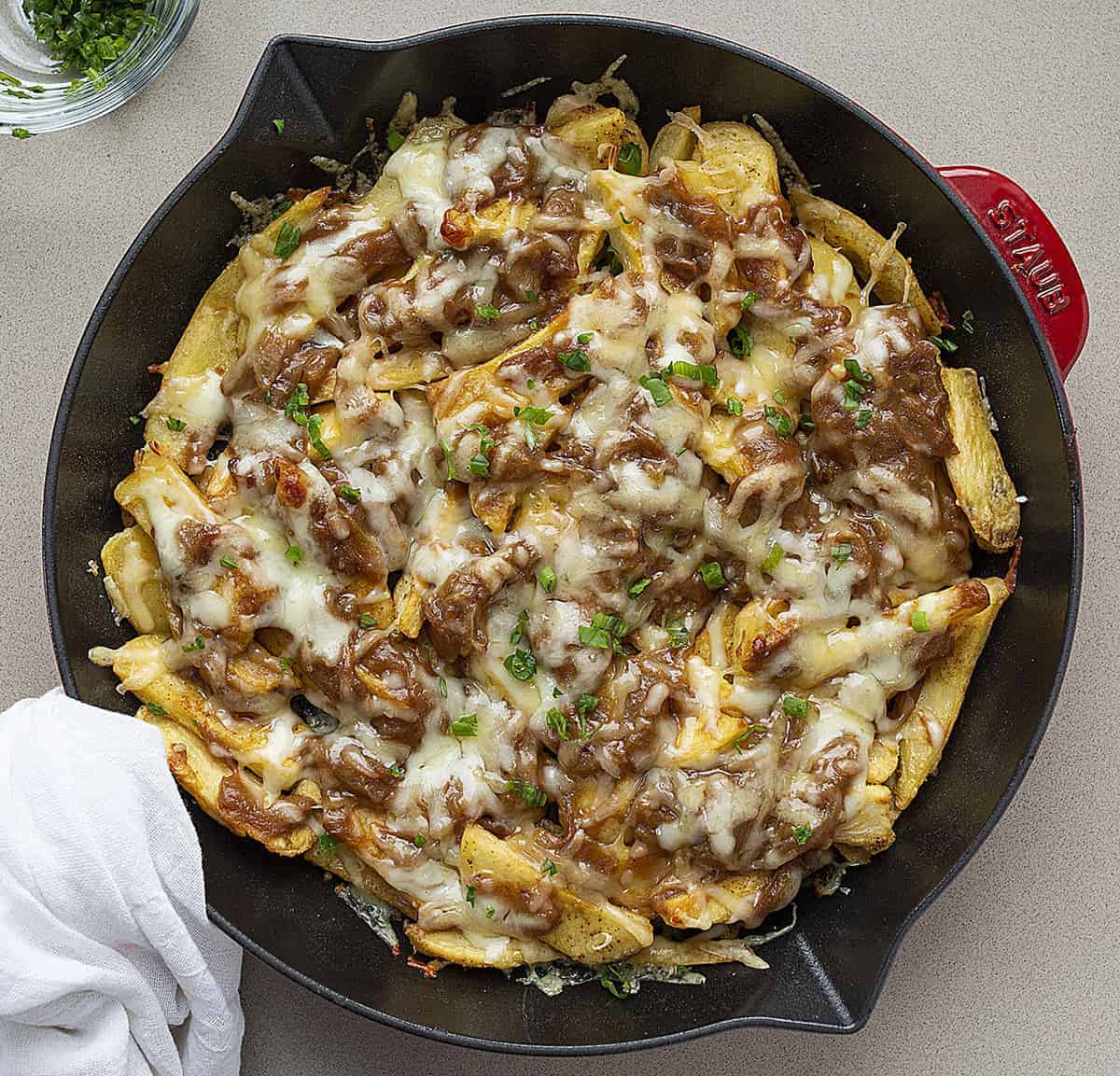Overhead Image of French Onion Cheesy Fries in a Red Skillet with Fresh Parsley 