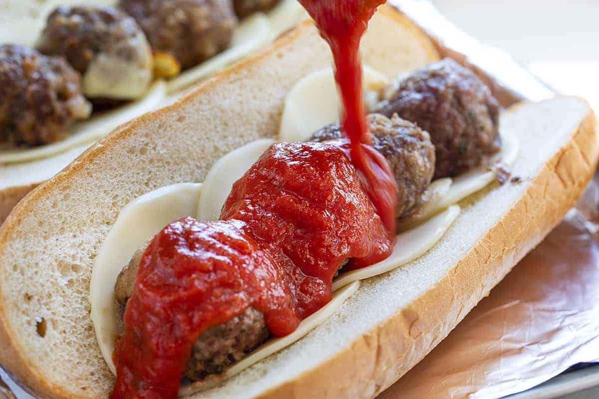 Stuffed Meatball Hoagie with Marinara Being Poured Over Meatballs