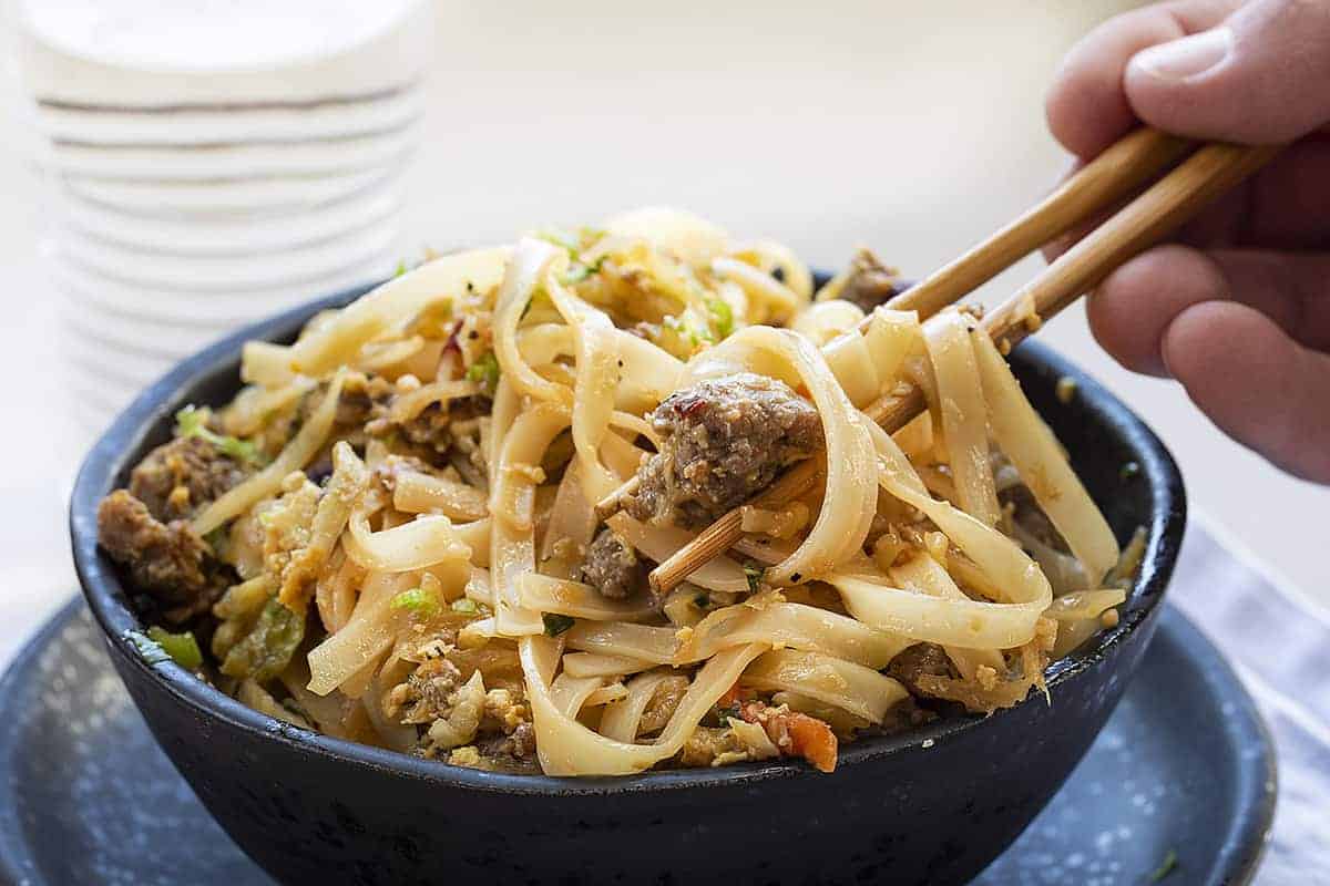 Bowl of Potsticker Noodles Being Picked up with Chopsticks