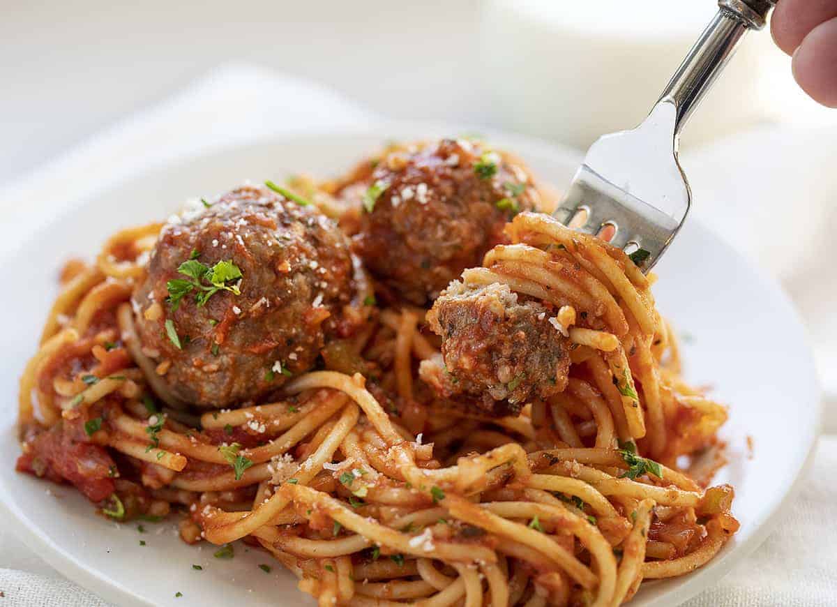 Fork picking up meatball and sauce coated spaghetti noodles