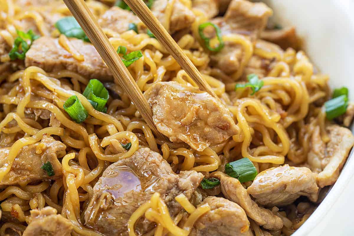 Easy Spicy Pork Noodles in Bowl Being Picked up with Chop Sticks