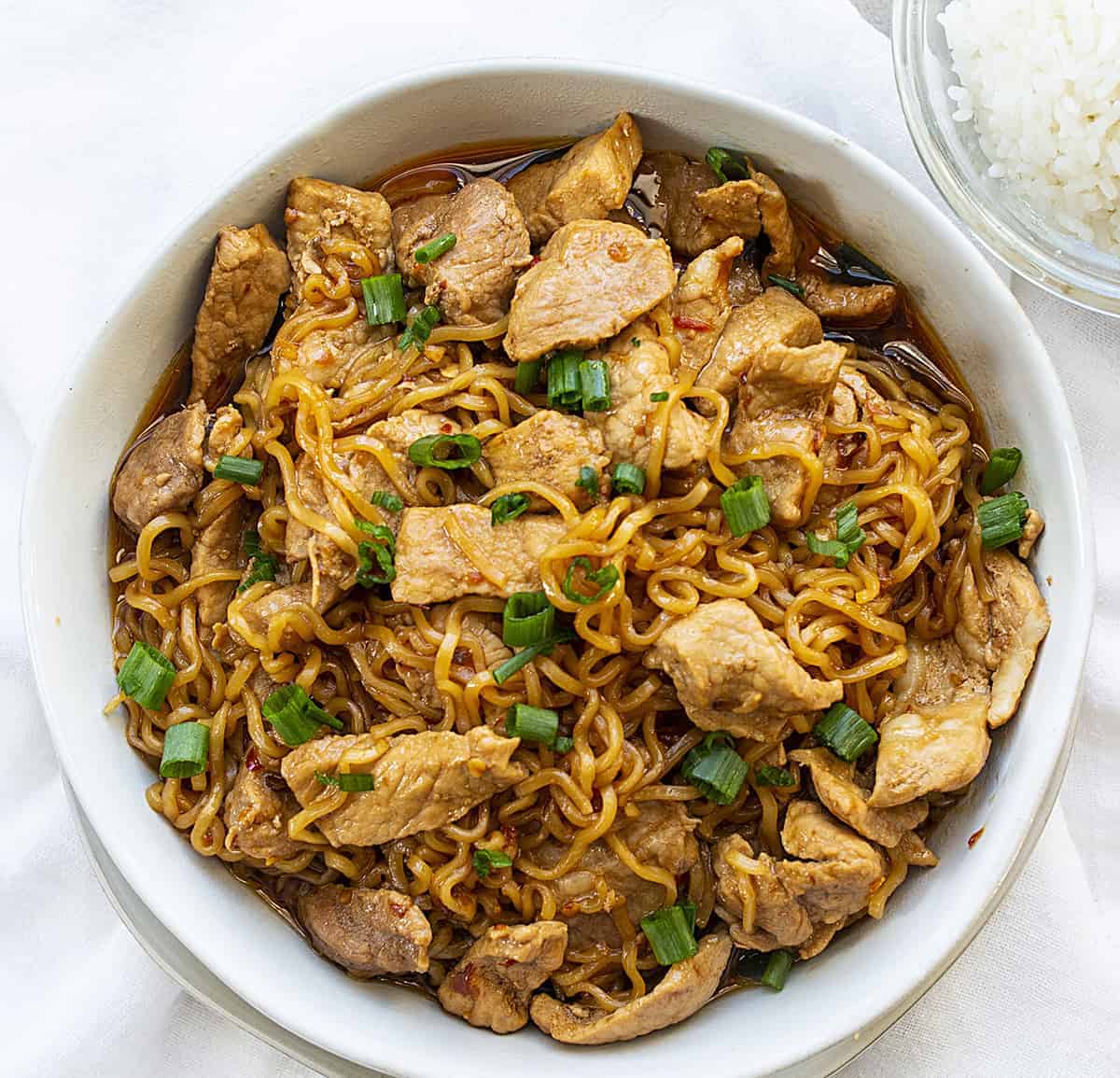 Overhead View of Easy Spicy Pork Noodles in White Bowl with White Rice on the Side