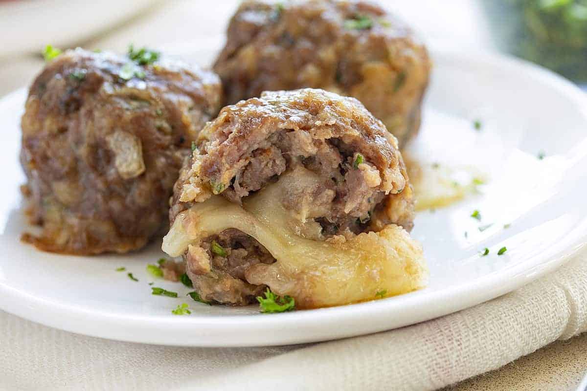 Cheese Stuffed Meatball Cut Into a White Plate