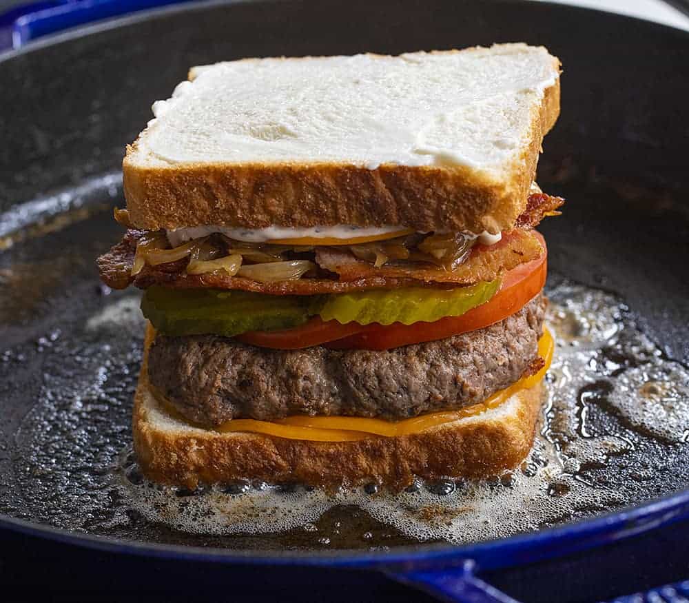 Bacon Cheeseburger Patty Melt in a Skillet About to Get Flipped