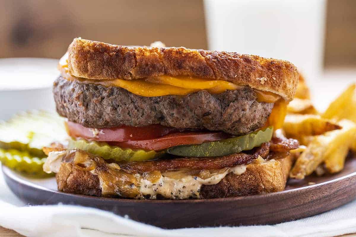 Bacon Cheeseburger Patty Melt on a Plate with French Fries and Pickle