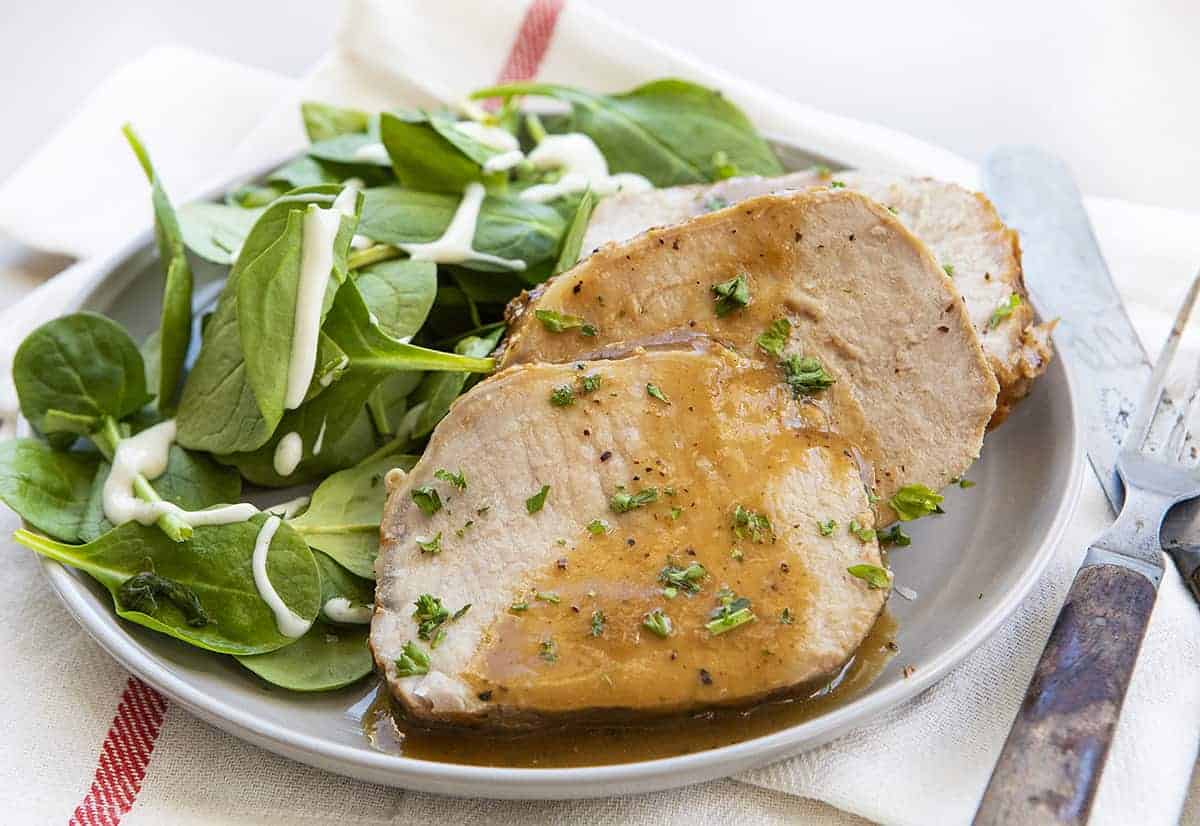 Roasted Pork Loin with Gravy on Gray Plate with Fresh Greens