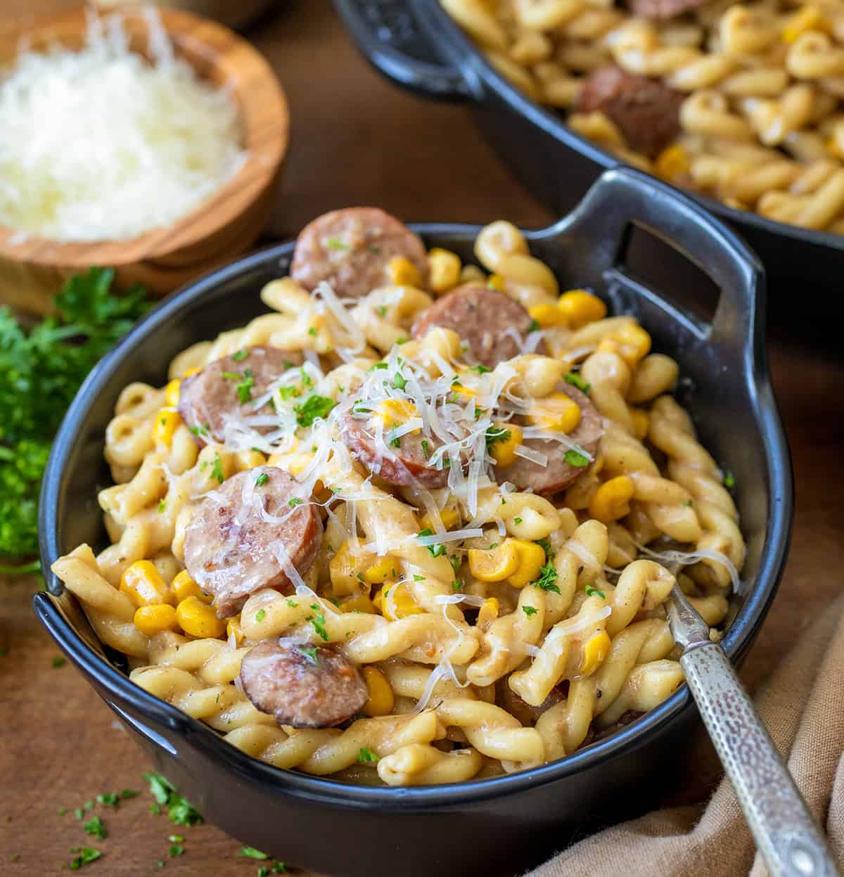 Bowl of Smoked Sausage Pasta on a wooden table by the skillet.