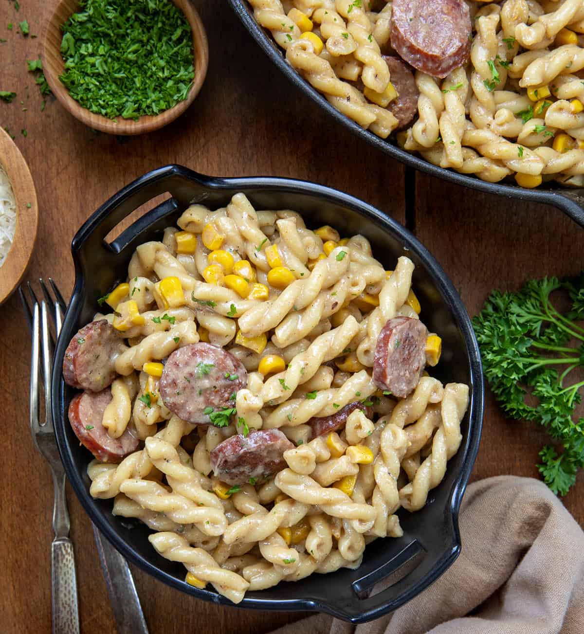 Bowl of Smoked Sausage Pasta on a wooden table by the skillet.